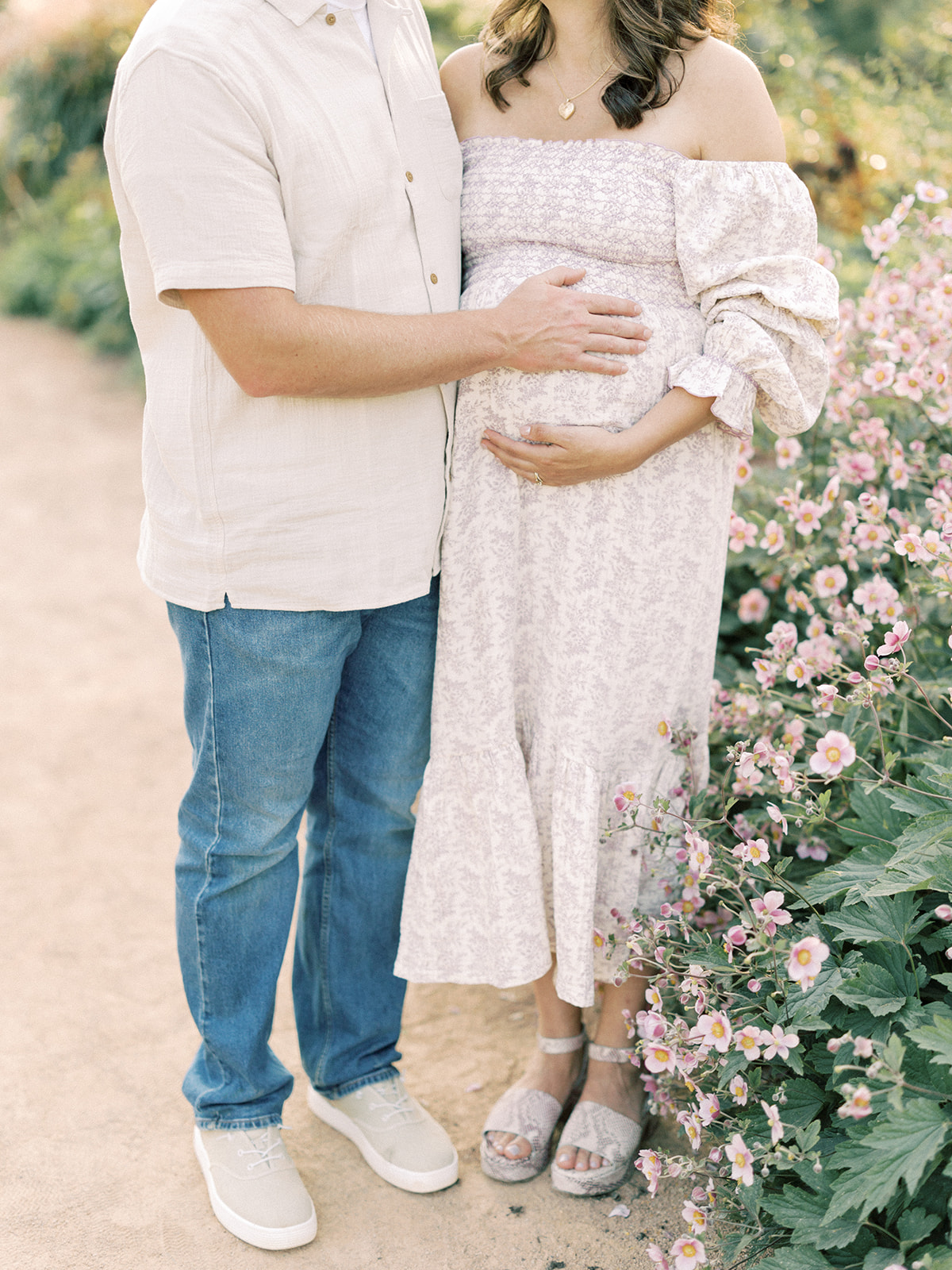 Details of expecting parents in a garden with hands on the bump after visiting baby shower venues in Minneapolis