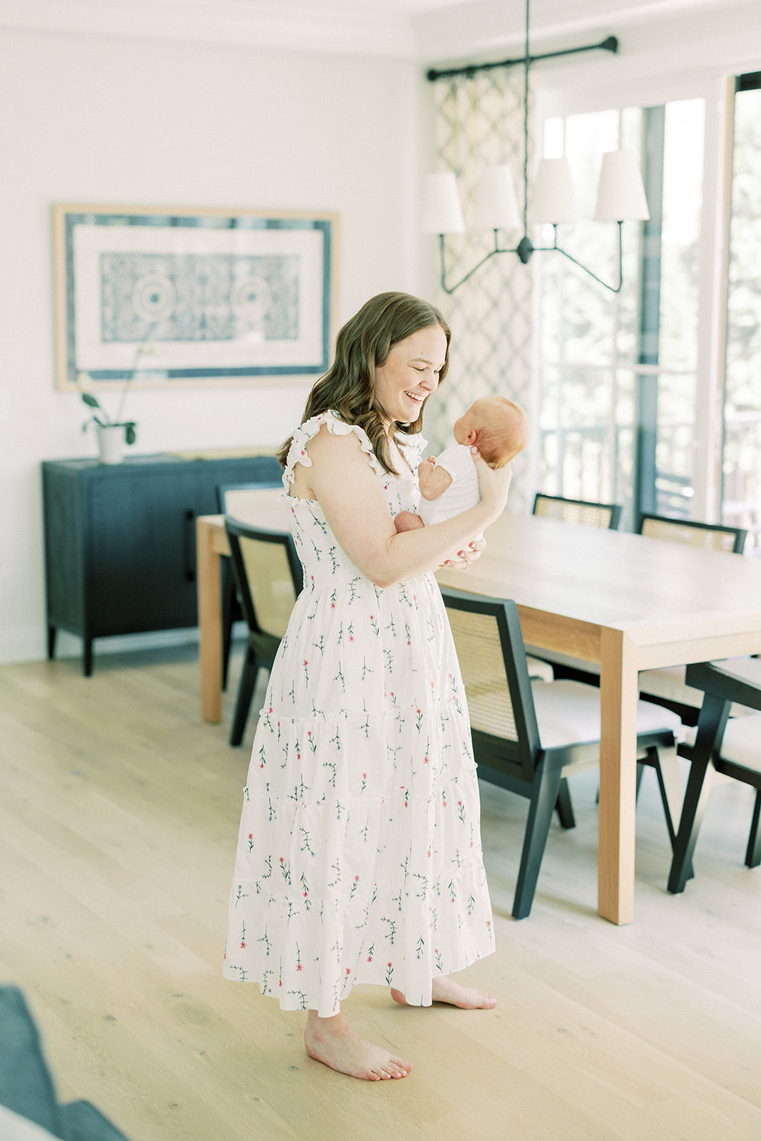 A happy new mom plays with her baby in a white dress from maternity stores in Minneapolis