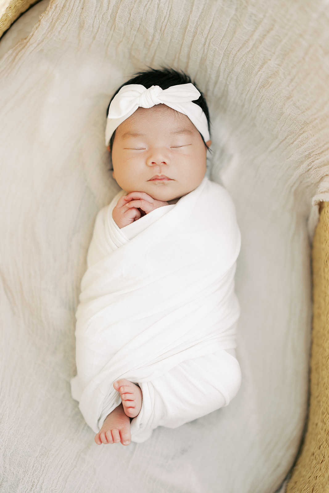 A newborn baby girl sleeps in a tight white swaddle in a crib after mom used maternity stores in Minneapolis